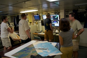 Four members of the Wood's Hole AUF-Sentry team watch the monitors. Masako and Maurice, the two chief scientists are also there, maps spread out in front of them.