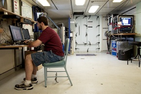 Matt sits down at the public terminal to check his email. Again. Behind him is the door of the main lab to the 01 deck, with its 17 latches.