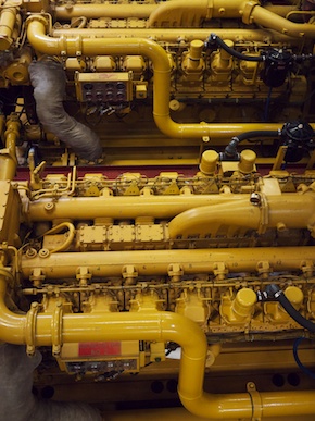 The generators are metal structures about three meters wide, one meter tall, and one meter deep. Pipes and pistons over the tops, dials and cords cover the sides.